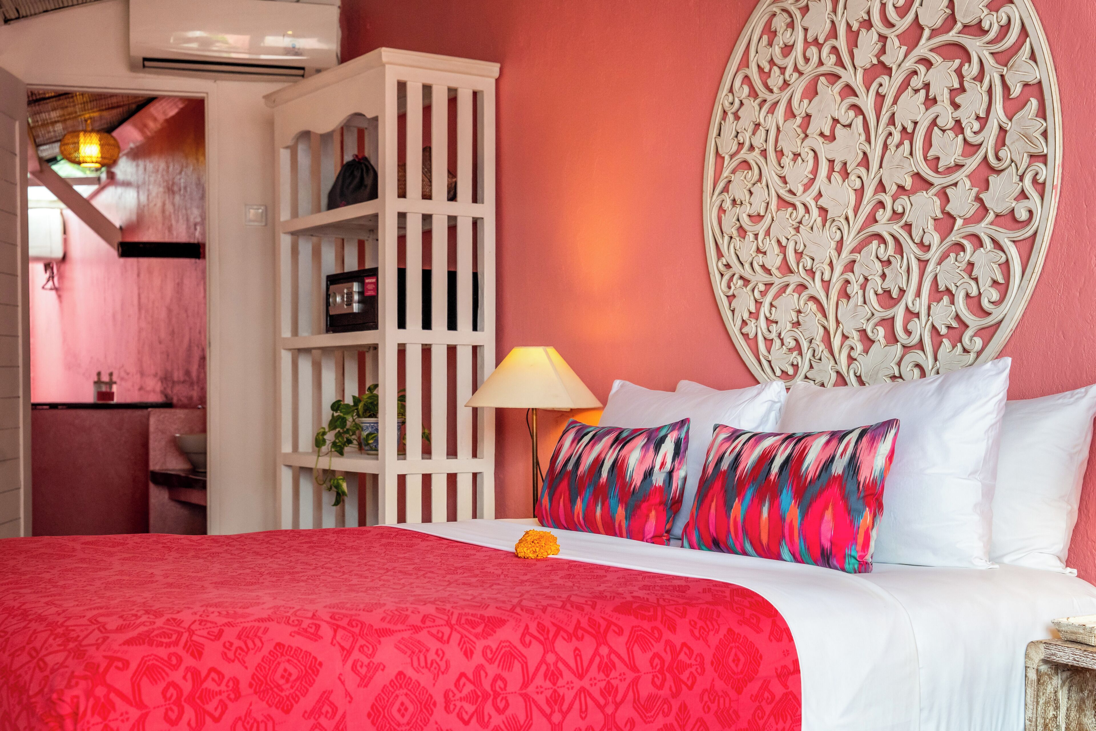 A room with a bed, a white wardrobe, a decorative wall piece, and a lamp.