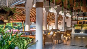 Un espacio exterior con mobiliario de mimbre, plantas colgantes y una zona de bar con estanterías.