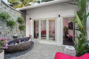 A spa area with a stone bathtub, a small white table, and a bench.