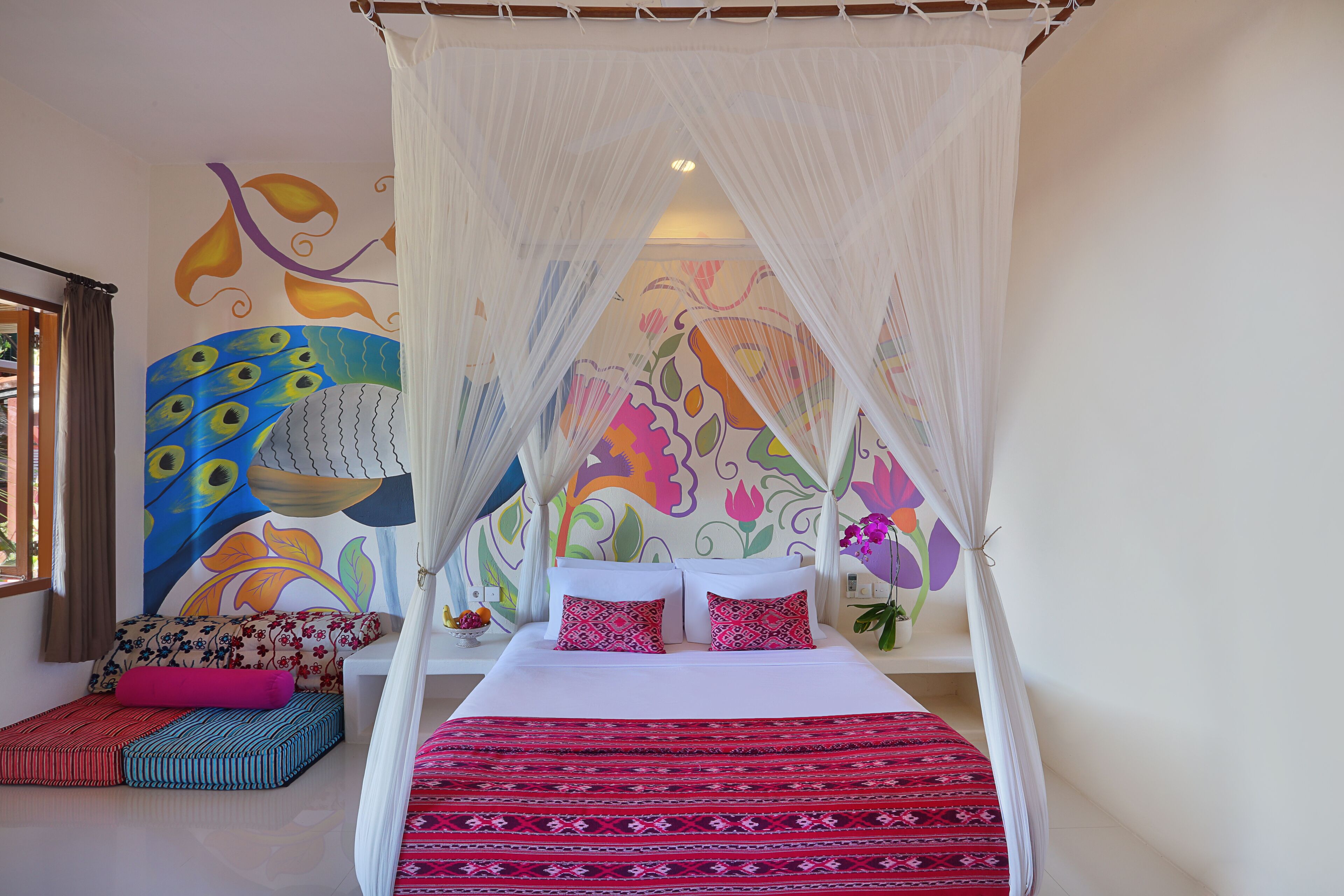 A room with a bed, colorful wall art, and a canopy bed.