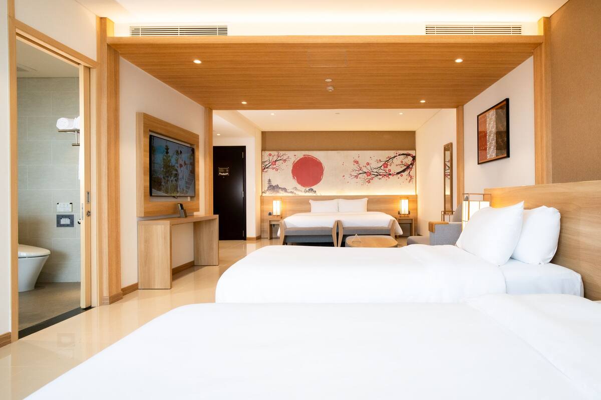 Een hotelkamer met een groot bed, een bureau, een stoel, een televisie en een badkamer die door een geopende deur zichtbaar is.