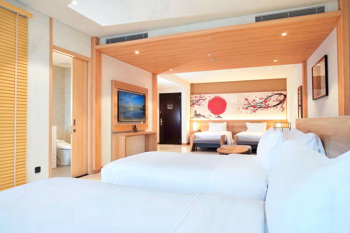 Een hotelkamer met twee bedden, een televisie, een schilderij en uitzicht op buiten.