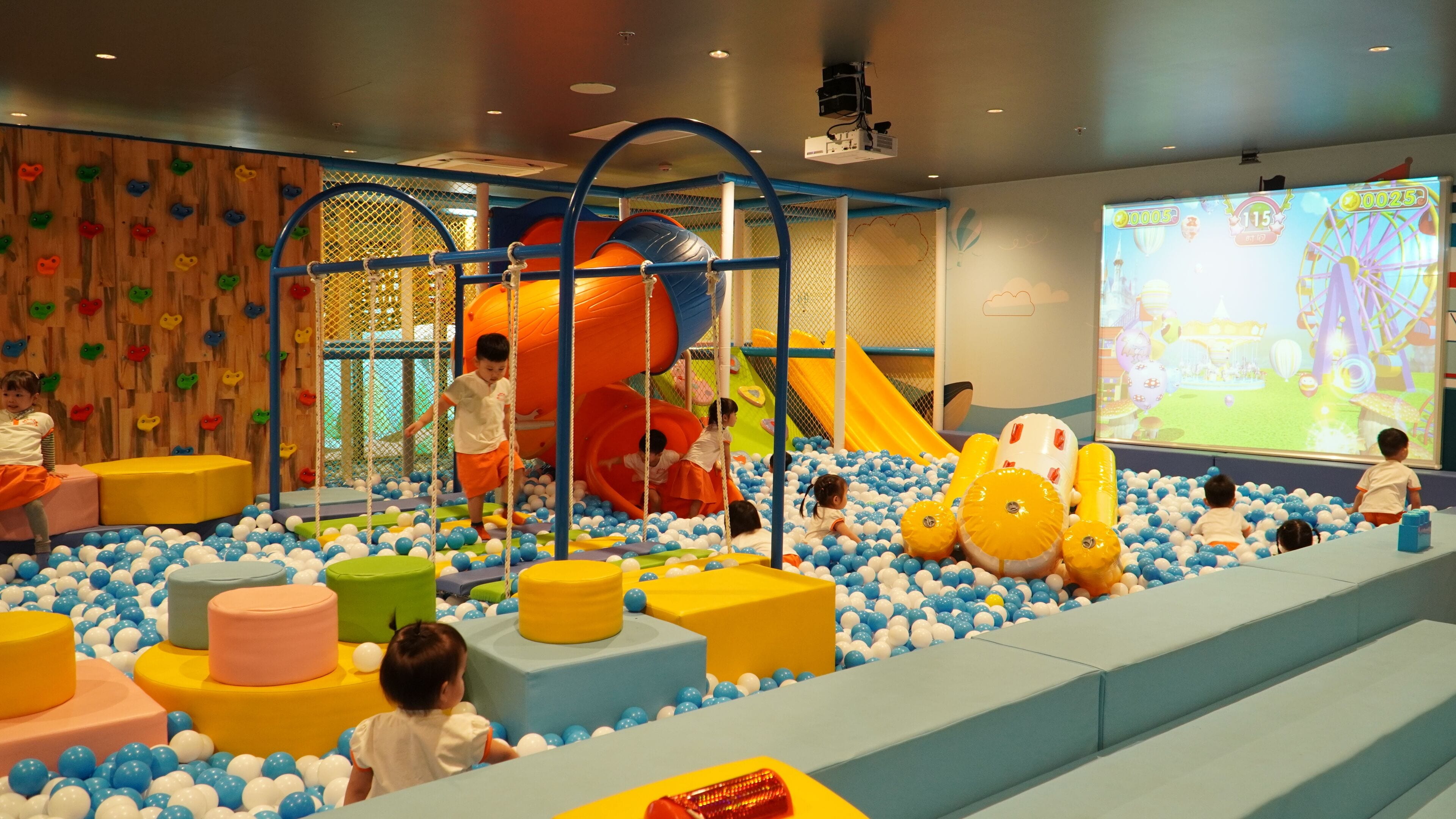 Zona de jocs infantil amb bressol de pilotes, parets d'escalada i tobogan.