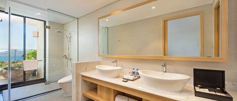 A modern bathroom with a glass shower enclosure, two sinks, a large mirror, and a wooden vanity.