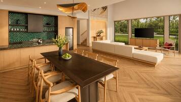 Una cocina moderna con comedor, piso de madera y un amplio ventanal con vista a la vegetación.