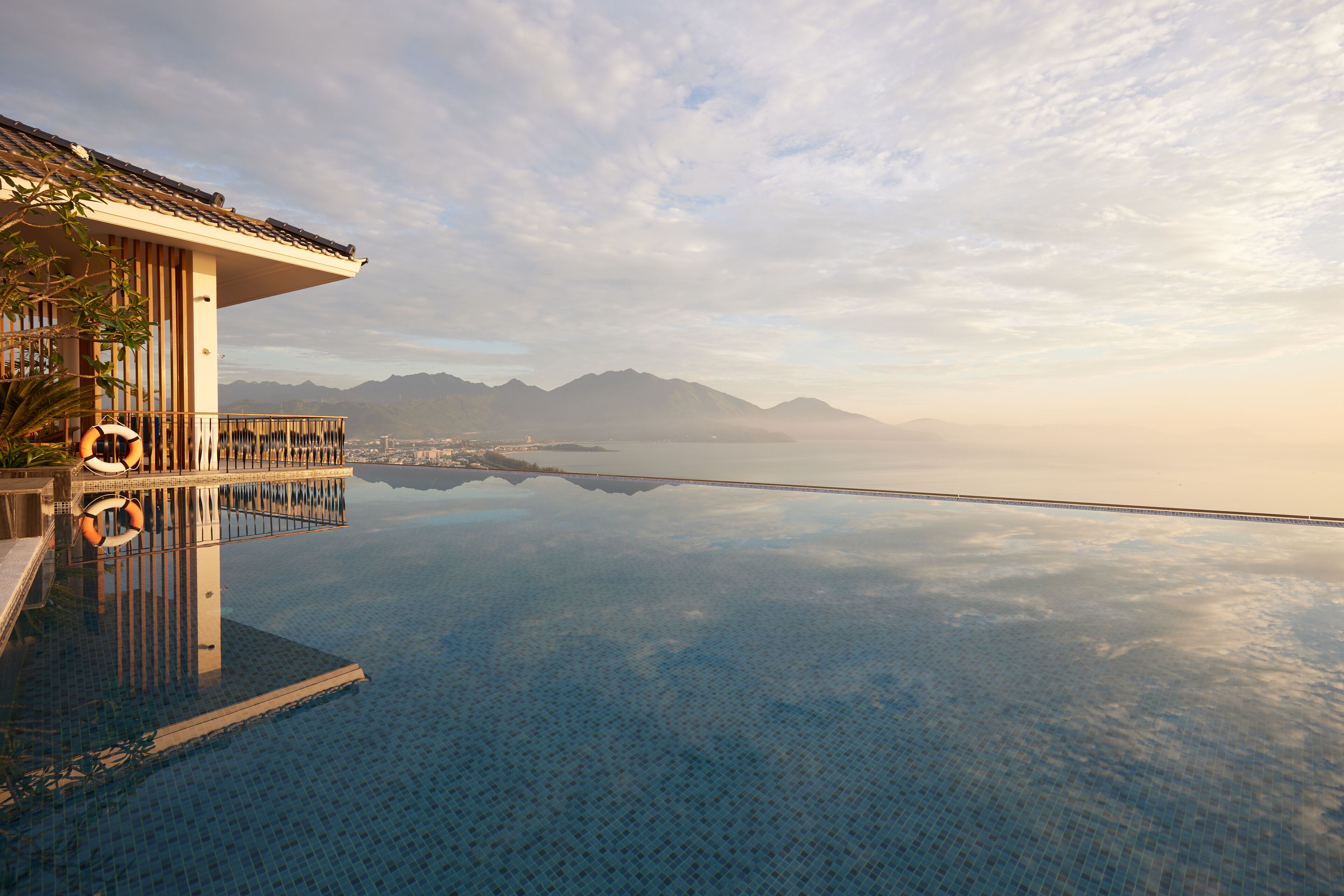 Una piscina infinita con vistas despejadas a montañas y un paisaje urbano al fondo.