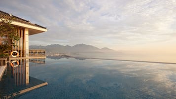 Una piscina infinita con vistas despejadas a montañas y un paisaje urbano al fondo.