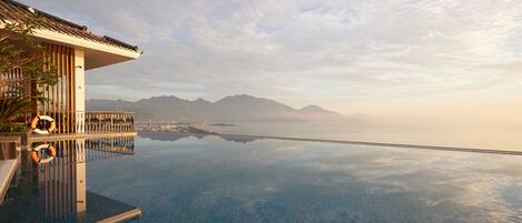 An infinity pool with a clear view of mountains and a cityscape in the background.