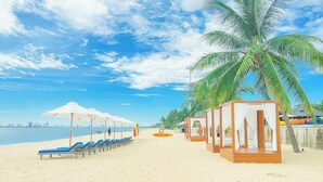 Una playa con tumbonas, sombrillas y cabañas de madera.