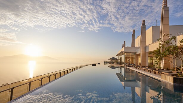 Una piscina infinita con vista al océano y al atardecer.