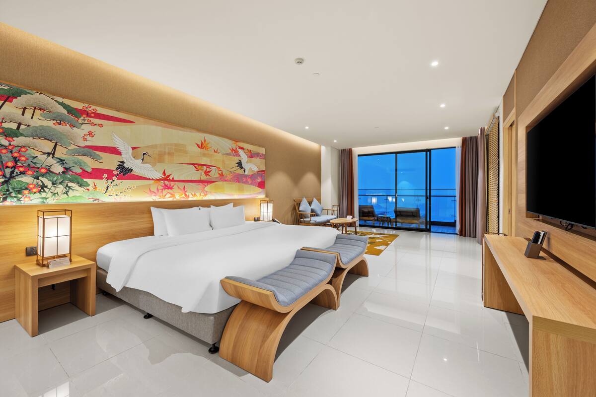 Een moderne hotelkamer met een groot bed, een televisie en uitzicht op de stad.