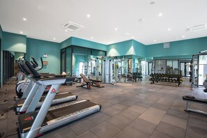 A gym with treadmills, weight machines, and dumbbells.