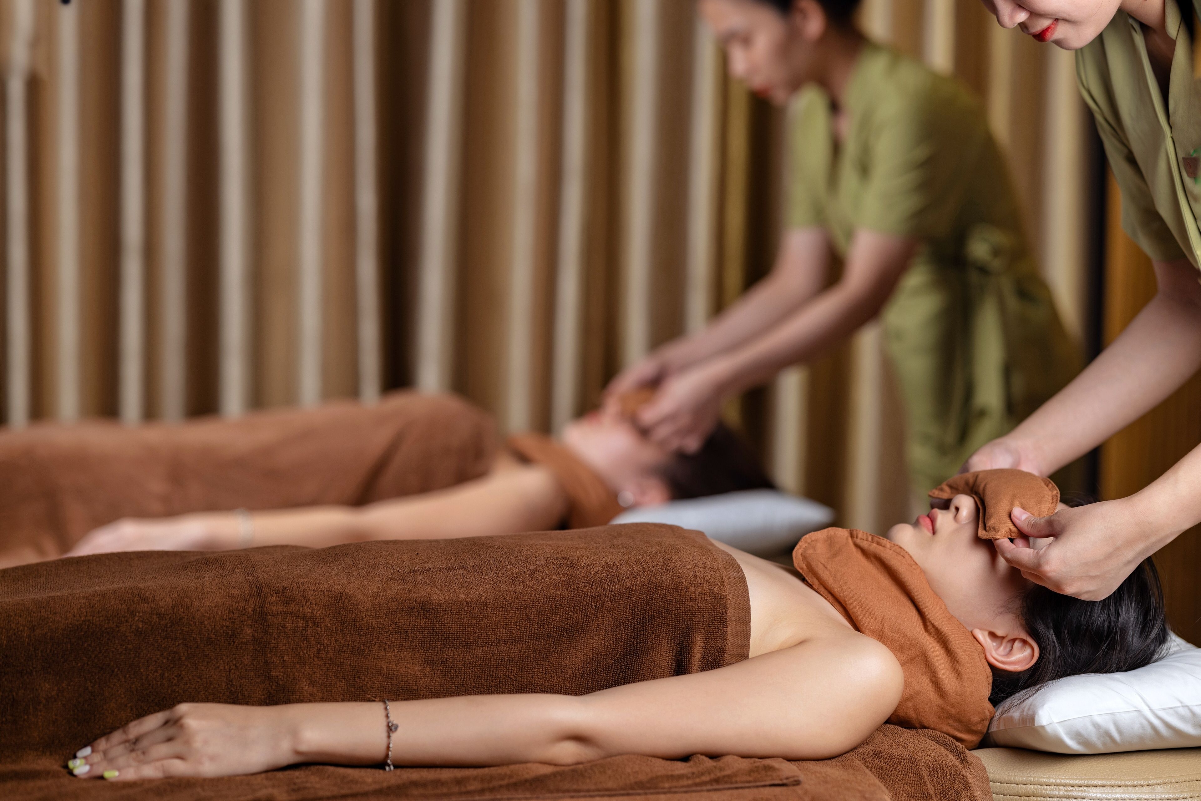 A person receiving a facial treatment in a room with a brown towel and a white pillow.