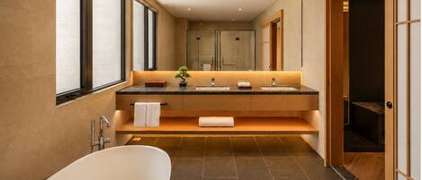 A modern bathroom with a freestanding bathtub, a vanity with two sinks, and a large mirror.