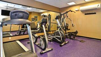 A gym with exercise equipment, a mirrored wall, and an air conditioning unit.