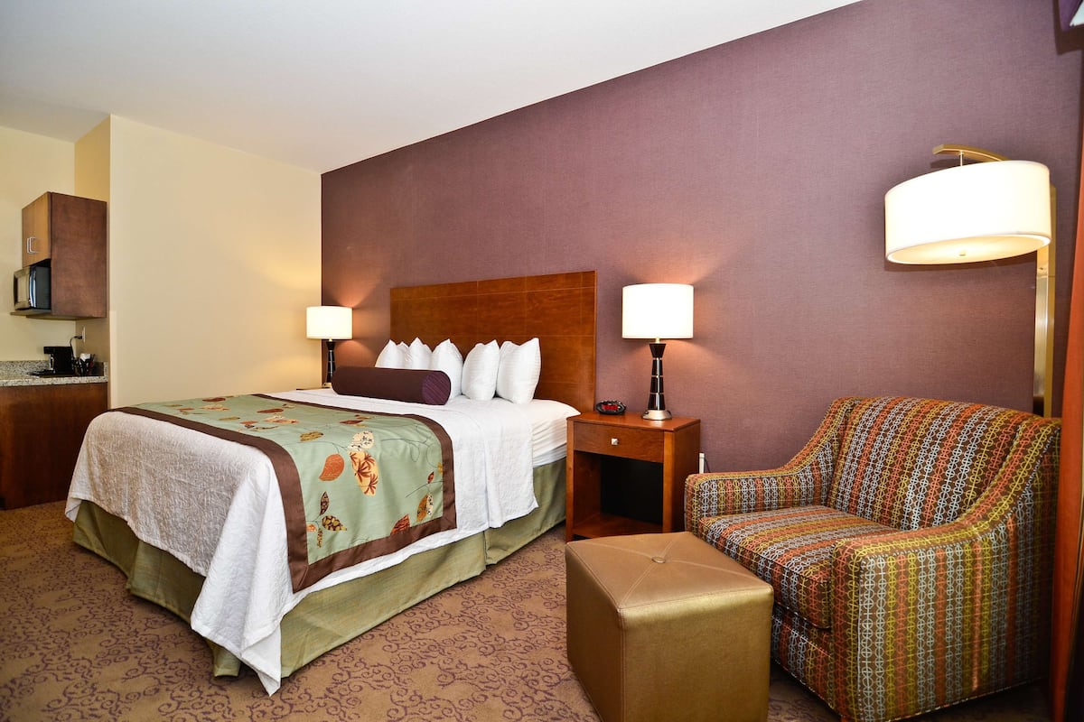 A hotel room with a bed, bedside lamps, a sofa, and a small table.