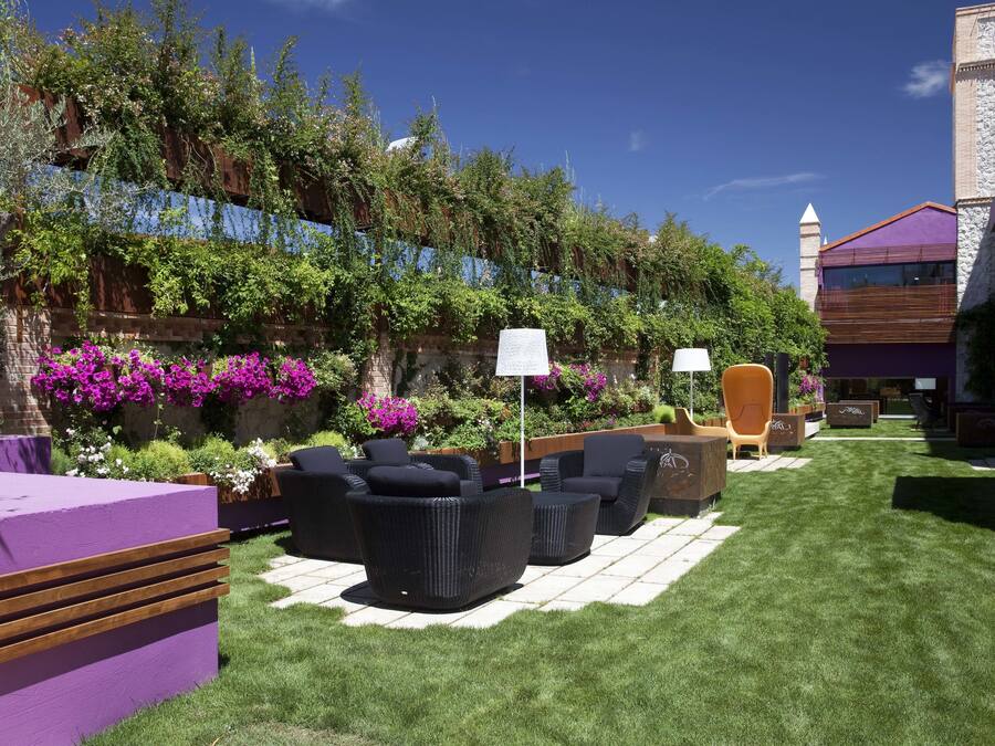 An outdoor seating area with modern furniture, a well-maintained lawn, and a lush garden with flowering plants.