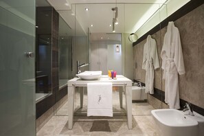 Un baño moderno con cabina de ducha de vidrio, tocador blanco con lavamanos, bidé y espejo.