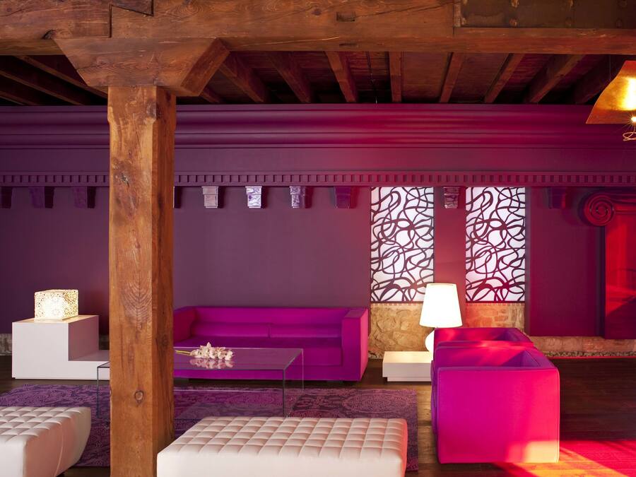 A modern living room with a purple sofa, a white coffee table, and a pink ottoman.