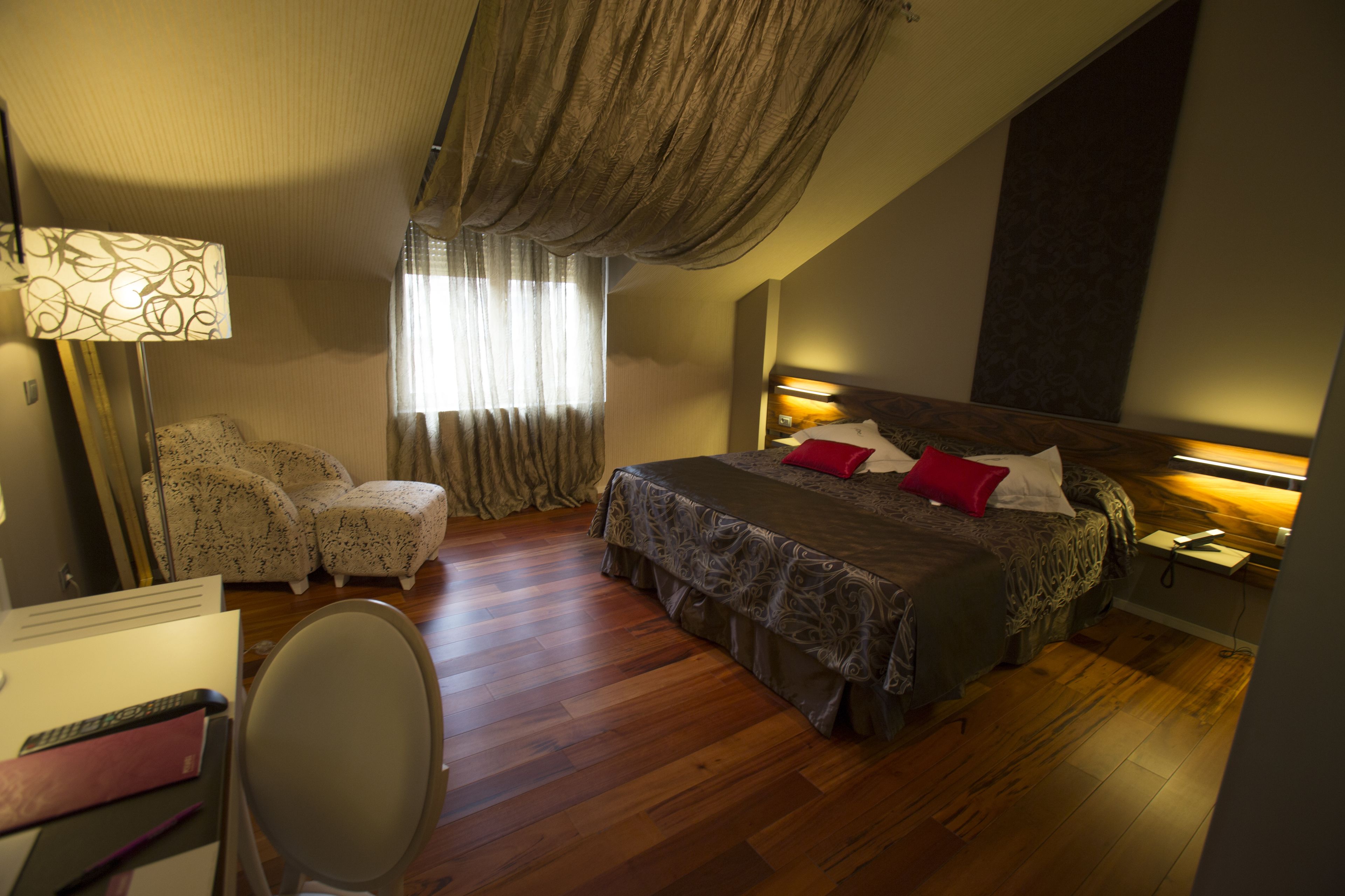 A bedroom with a bed, a desk, a chair, and a window with curtains.