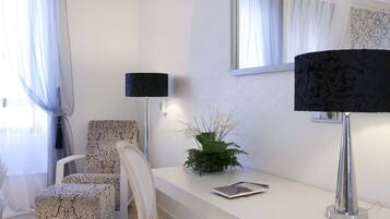 Une pièce moderne et bien éclairée, avec un bureau blanc, deux chaises, une lampe noire et un miroir.