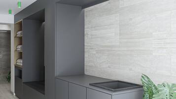A modern bathroom with a grey cabinet, a sink with a textured countertop, and a green plant.