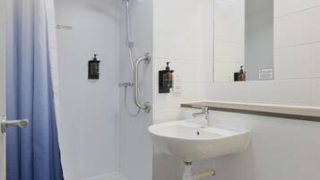 A bathroom with a shower, sink, toilet, and a mirror.