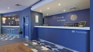 Zona de recepción con pared azul, un reloj y un cartel que dice 'hello & welcome'.