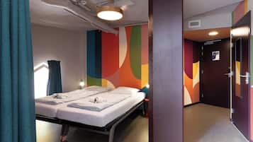 Een hotelkamer met een bed, een bureau, een stoel en een kleurrijke muur.