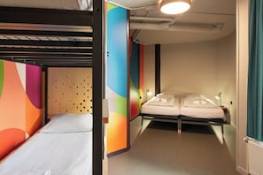 A hotel room with bunk beds, a bedside table with a lamp, and a colorful wall design. - Stayokay Rotterdam - Hostel to Stayokay Rotterdam - fully renovated April 2026 (Rotterdam)
