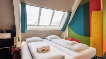 Quarto de hotel com duas camas, janela com cortinas, pia, espelho, mesa de cabeceira e parede colorida.