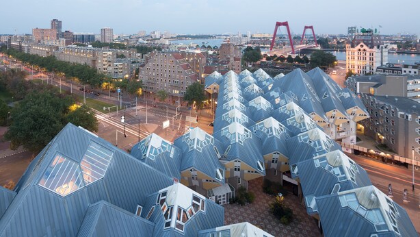 A cluster of uniquely shaped blue-roofed buildings with multiple windows, set in an urban area with a bridge in the background. - Stayokay Rotterdam - Hostel to Stayokay Rotterdam - fully renovated April 2026 (Rotterdam)