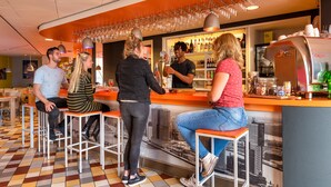 A bar area with stools, a counter, and a bartender. - Stayokay Rotterdam - Hostel to Stayokay Rotterdam - fully renovated April 2026 (Rotterdam)