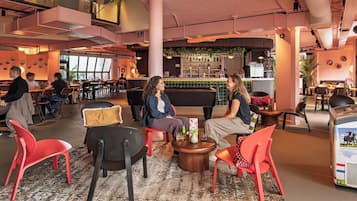 Un espacio interior moderno con zonas de estar, un bar y una mesa de billar.