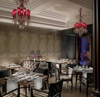 Un'area da pranzo con diversi tavoli apparecchiati, eleganti lampadari e piastrelle a motivi decorativi.
