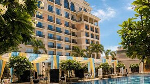 A hotel with a swimming pool, multiple balconies, and lush greenery.