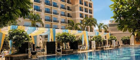 Un hotel con piscina, varios balcones y abundante vegetación.