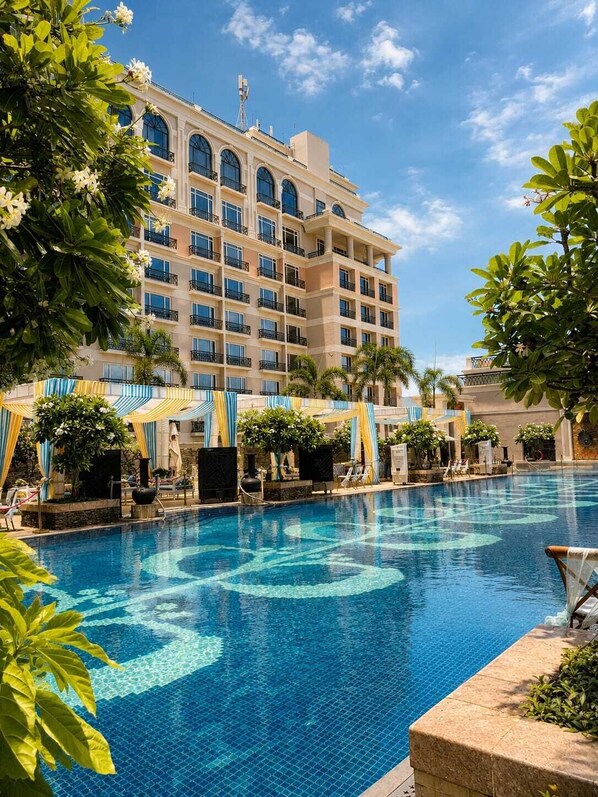 Un hotel con piscina, varios balcones y abundante vegetación.