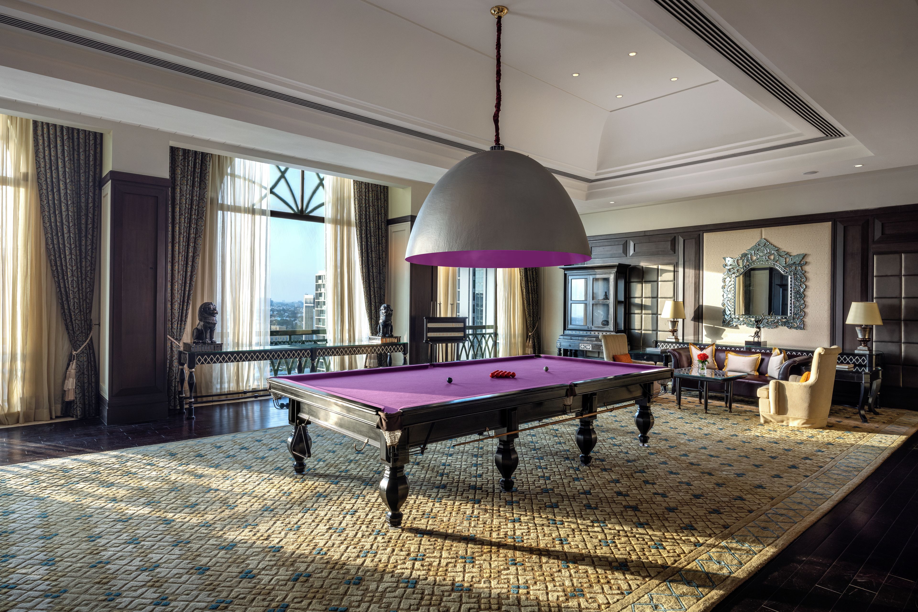 Una habitación amplia con mesa de billar, un gran candelabro y vistas a la ciudad.