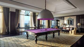 Una habitación amplia con mesa de billar, un gran candelabro y vistas a la ciudad.