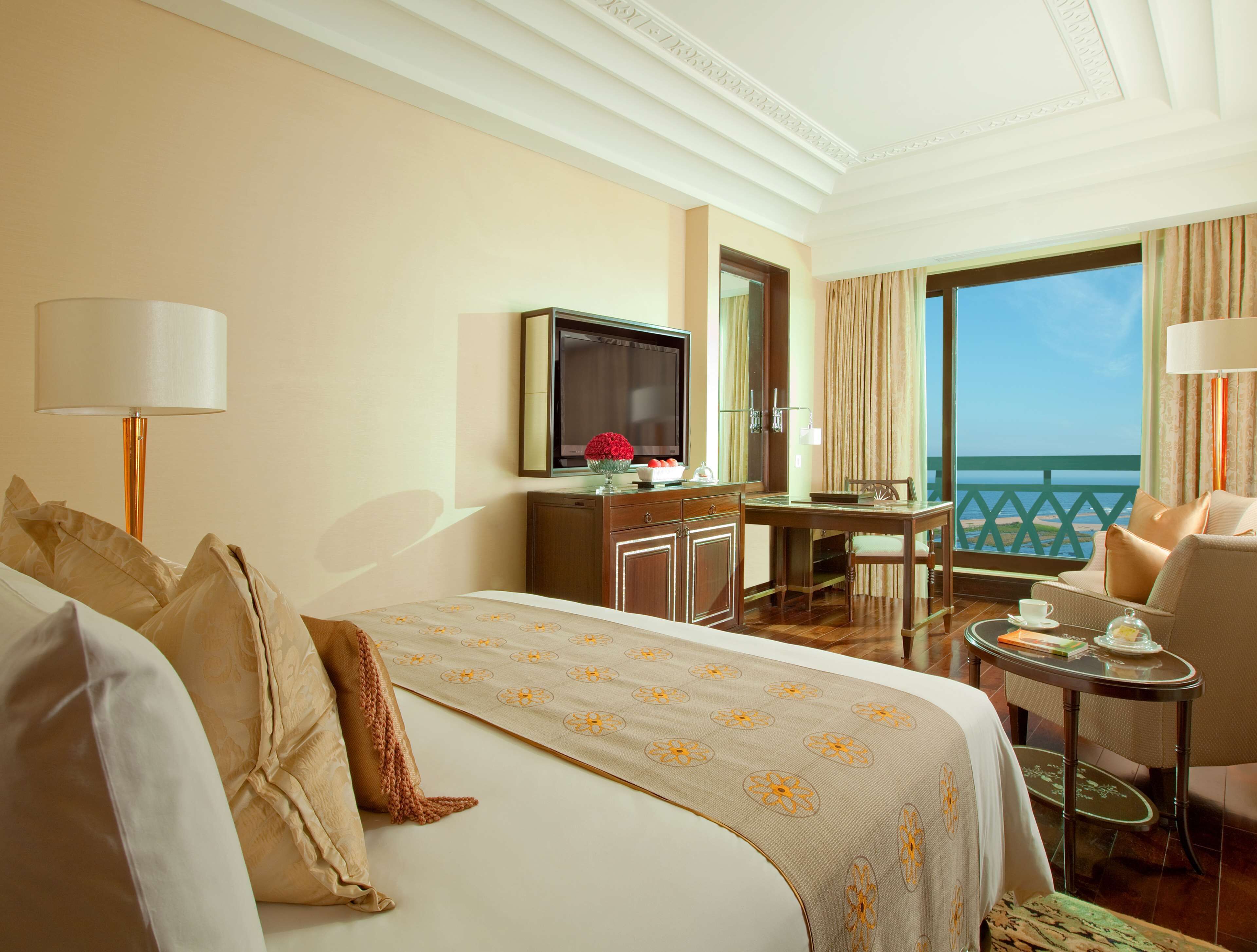 Una habitación de hotel con cama, escritorio, televisor y vistas al mar.