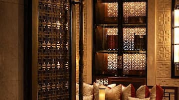 A traditional interior with a wooden door, a cushioned seating area, and a patterned wall.