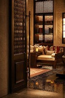 A traditional interior with a wooden door, a cushioned seating area, and a patterned wall.