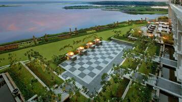 Terraço no telhado com piso xadrez, área de estar externa e vista para um lago e terras distantes.
