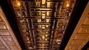 A corridor with a patterned ceiling, a central illuminated walkway, and a bar area on the right.
