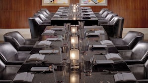 A conference room with a long table, black leather chairs, and framed artwork on the walls. - The Leela Palace Chennai (Chennai)
