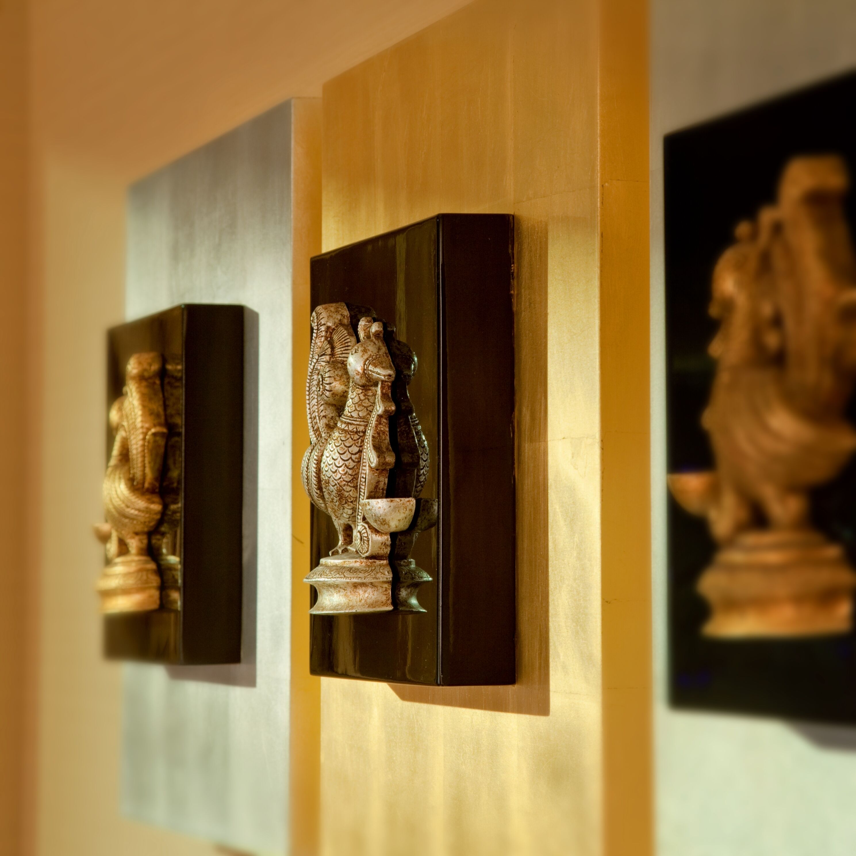 Tres esculturas fijadas en una pared.