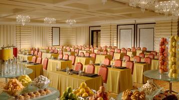 A banquet hall with rows of tables, chairs, and chandeliers.