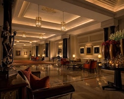Un'ampia hall con pavimento in marmo lucido, arredi eleganti e lampade decorative.