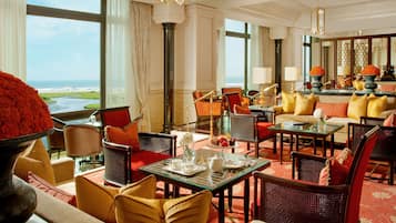 A spacious hotel lobby with a view of the ocean, furnished with comfortable seating and a dining area.